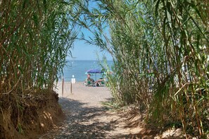 A pathway leading to a beach with umbrellas and beach chairs. - Two-room Apartment with Veranda and Garden 100m from the Sea - Villaggio Sole e Mare (Rio)