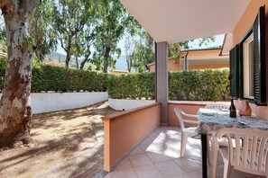 An outdoor patio area with a table and chairs, surrounded by a low wall and a hedge. - Two-room Apartment with Veranda and Garden 100m from the Sea - Villaggio Sole e Mare (Rio)
