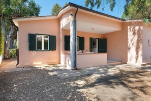 A single-story building with a flat roof, a covered patio area, and a gravel driveway. - Two-room Apartment with Veranda and Garden 100m from the Sea - Villaggio Sole e Mare (Rio)