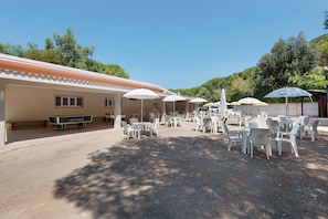 An outdoor seating area with tables and chairs, umbrellas, and a pool table. - Two-room Apartment with Veranda and Garden 100m from the Sea - Villaggio Sole e Mare (Rio)