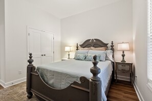 Een slaapkamer met een hemelbed, twee nachtkastjes en een deur.