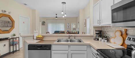 A modern kitchen with a dishwasher, double sink, and a microwave.