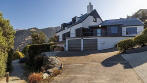 Ein modernes, zweistöckiges Haus mit Garage, umgeben von einer Schotterauffahrt und einem angelegten Garten.