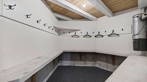 A corner room with a sloped ceiling, a concrete floor, and a clothes drying rack with hangers. - Alpine Haven on Poole Lane (Queenstown)