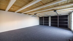 Eine Garage mit geneigter Decke, einem grauen Boden und einer geschlossenen Garagentür.