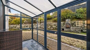 A conservatory with a stone wall and a fireplace. - Alpine Haven on Poole Lane (Queenstown)