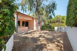 A residential property with a paved driveway, a covered patio area, and a well-maintained garden with hedges. - Two-room Apartment with Veranda and Garden 100m from the Sea - Villaggio Sole e Mare (Rio)