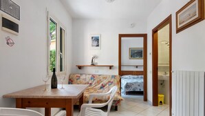 Een knusse kamer met een eettafel, stoelen, een bank, een bed en een kleine badkamer.