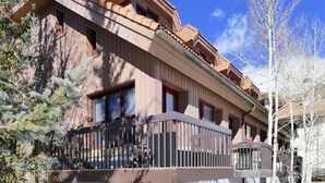 A multi-story building with a balcony on the second floor, a stone facade, and a clear sky. - Ski-In Ski-Out Retreat in the Heart of Mtn Village (Telluride)