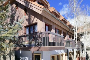 A multi-story building with a balcony on the second floor, a stone facade, and a clear sky. - Ski-In Ski-Out Retreat in the Heart of Mtn Village (Telluride)