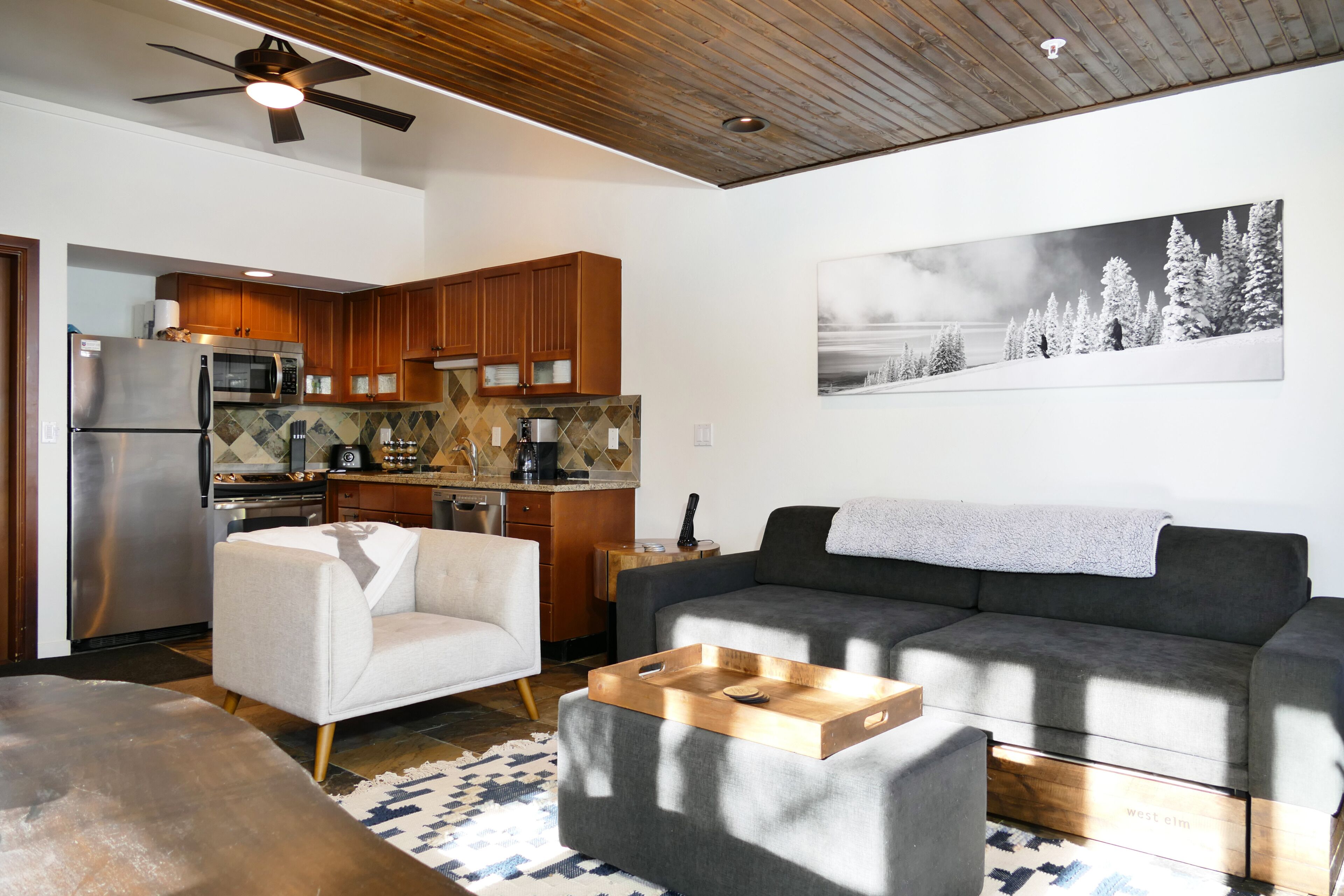 Una sala de estar moderna con un sofá gris, un sillón blanco y una mesa de centro de madera.
