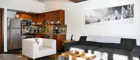 A modern living room with a grey sofa, a white armchair, and a wooden coffee table.