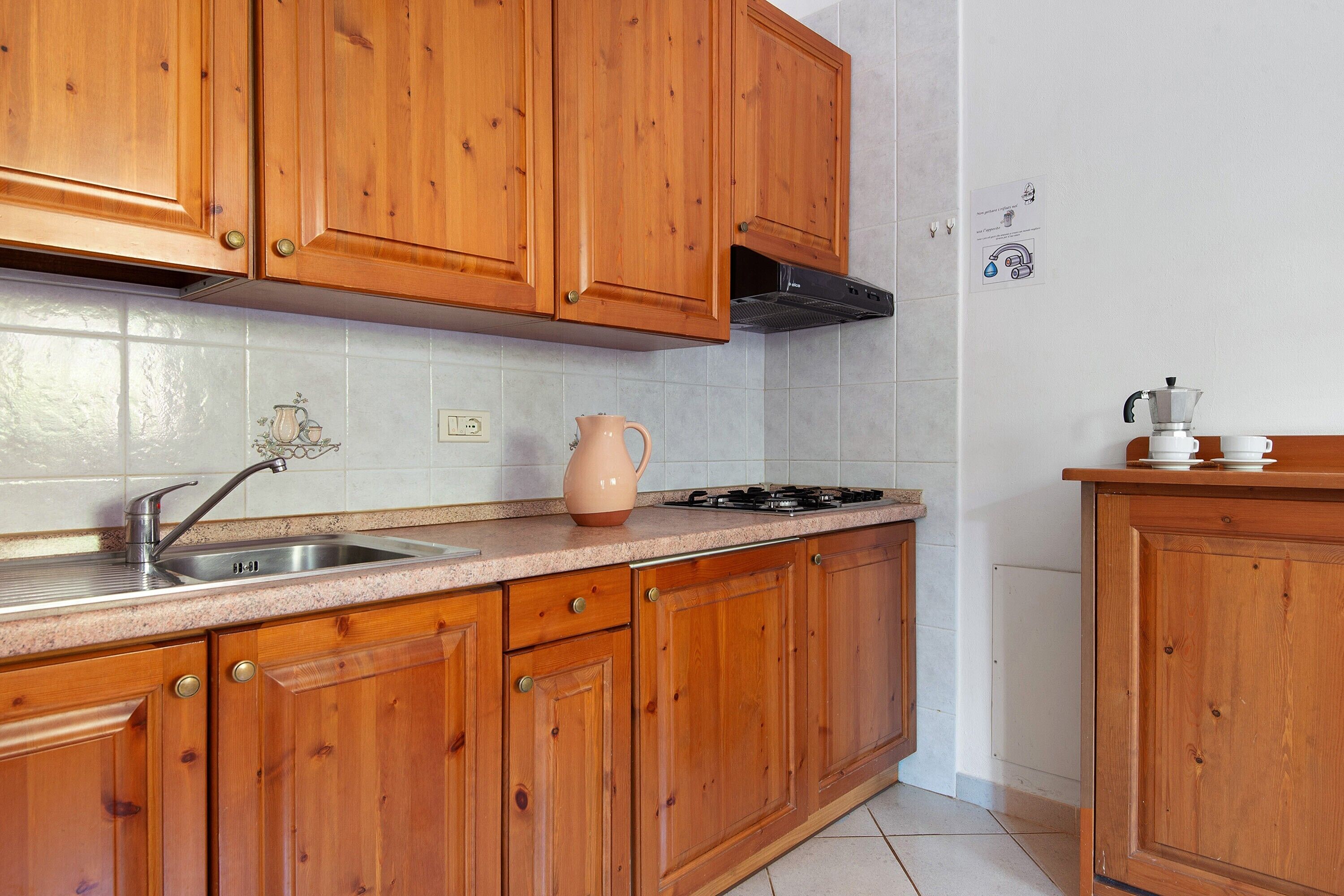 A kitchen with wooden cabinets, a stainless steel sink, a gas stove, and a coffee maker.