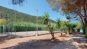 A fenced outdoor area with a dirt path, trees, and a view of a hilly landscape. - Two-room Apartment with Veranda and Garden 100m from the Sea - Villaggio Sole e Mare (Rio)