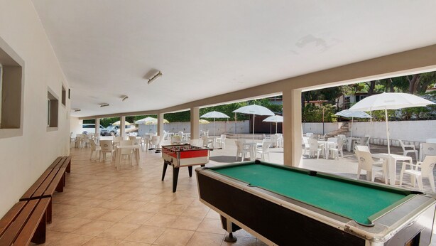 A pool table and foosball table in a covered outdoor area with white chairs and umbrellas. - Three-Room Apartment with Garden 100 Meters from the Beach - Sole e Mare Tourist Village (Rio)