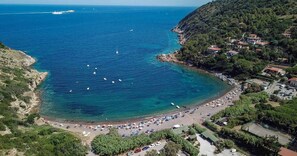 Eine Küstenlandschaft mit Strand, Booten und einer Siedlung am Hang.