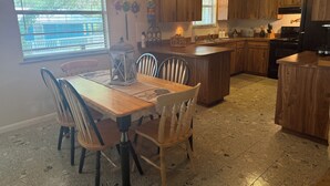 Una cocina con armarios de madera, una isla central y una mesa de comedor con sillas.