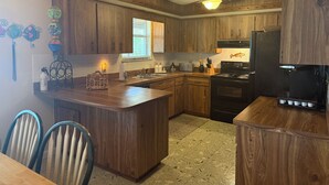 Una cocina con armarios de madera, una isla central, una estufa y un refrigerador.