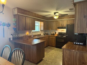 A kitchen with wooden cabinets, a central island, a stove, and a refrigerator.