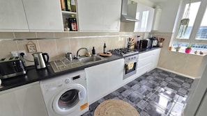 A compact kitchen with a washing machine, a sink, and a stove. - Bright and spacious 1 bedroom flat near Warren Street. Perfect to explore London (London)