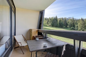 A balcony with a table, chairs, and a view of a forested landscape. - Apartment 'Family Lodge' with Mountain View and Balcony (Villard-de-Lans)