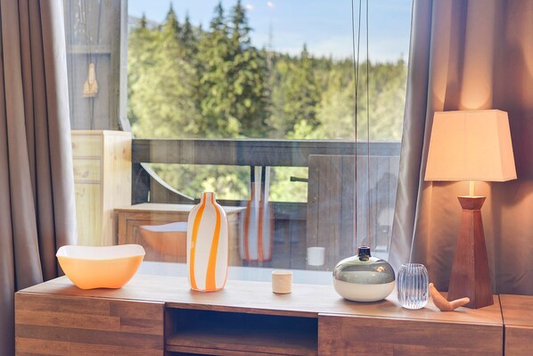 A wooden table with a bowl, a striped vase, a small container, a glass, and a lamp.