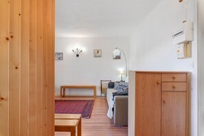 Een kamer met houten vloer, een bankje, een bank, een kleine tafel, een lamp en een kast.