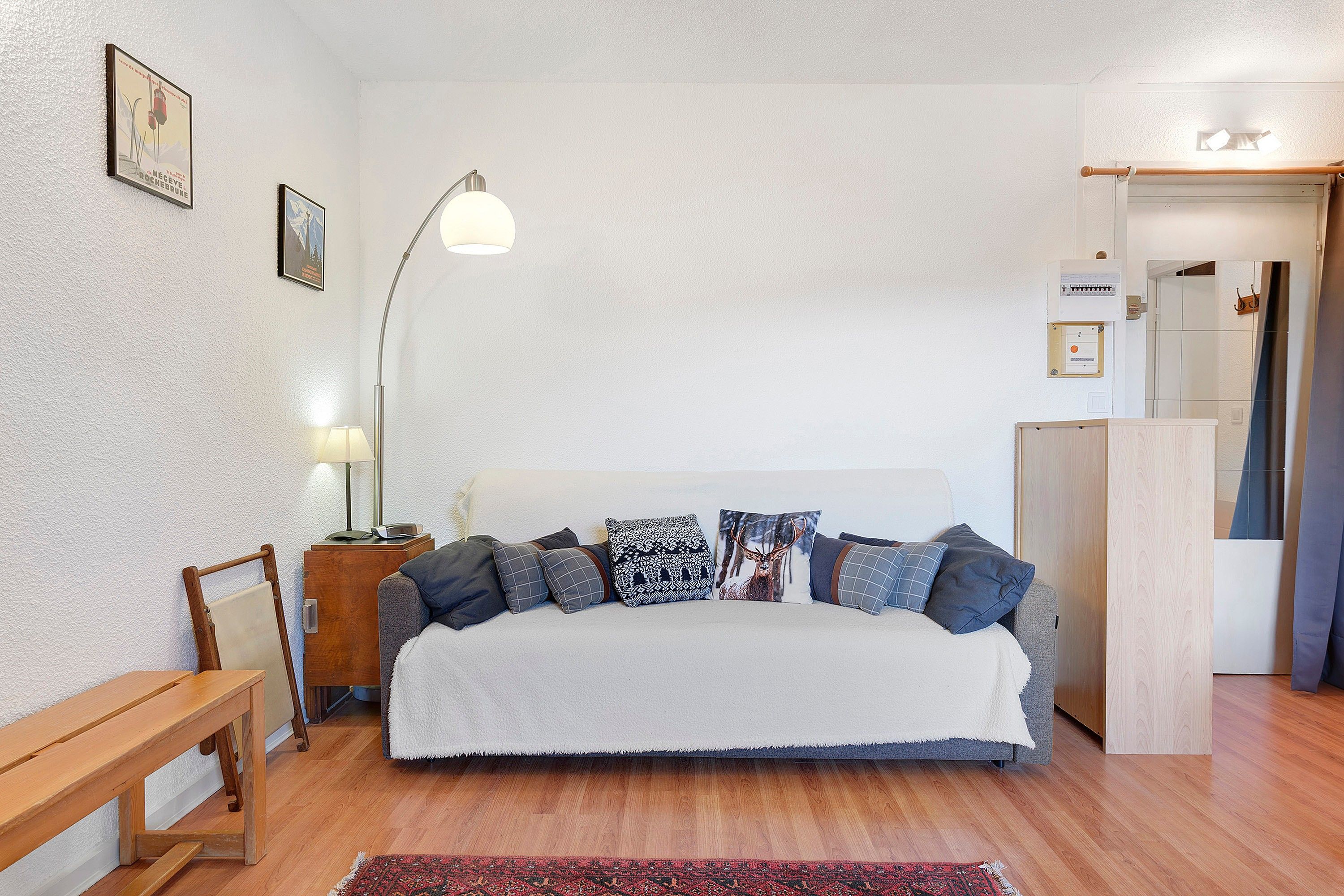Un dormitorio con cama, mesita de noche, lámpara y un banco de madera.