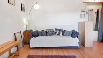 Un dormitorio con cama, mesita de noche, lámpara y un banco de madera.