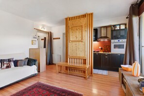 A compact living space with a sofa, a bench, a kitchen area, and a dining table.