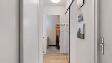 A hallway with a wooden floor, a door with a sign, and a wall-mounted picture.