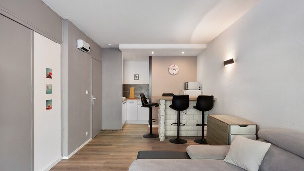 Un salon moderne avec un canapé et un coin repas équipé de tabourets de bar.
