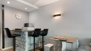 Une cuisine moderne avec un coin bar, comprenant des tabourets de bar, une table en bois et un four à micro-ondes.