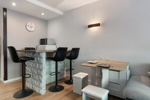A modern kitchen with a bar area, including bar stools, a wooden table, and a microwave.