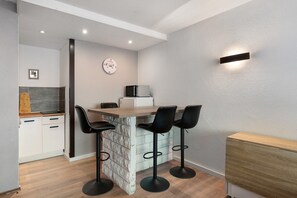 Een kleine keuken met een vast kookeiland, barstoelen en een magnetron.