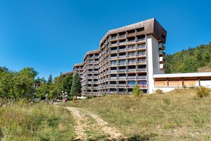 Een meerhoog hotel met balkons, een heldere lucht en een pad dat naar het gebouw leidt.