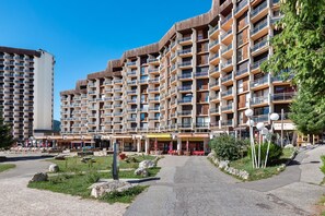 A multi-story hotel with balconies, outdoor seating, and a clear sky.