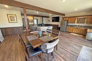 Eine geräumige Küche mit Holzschränken, ein Essbereich mit Tisch und Stühlen sowie ein Wohnbereich mit Sofa und Kamin.