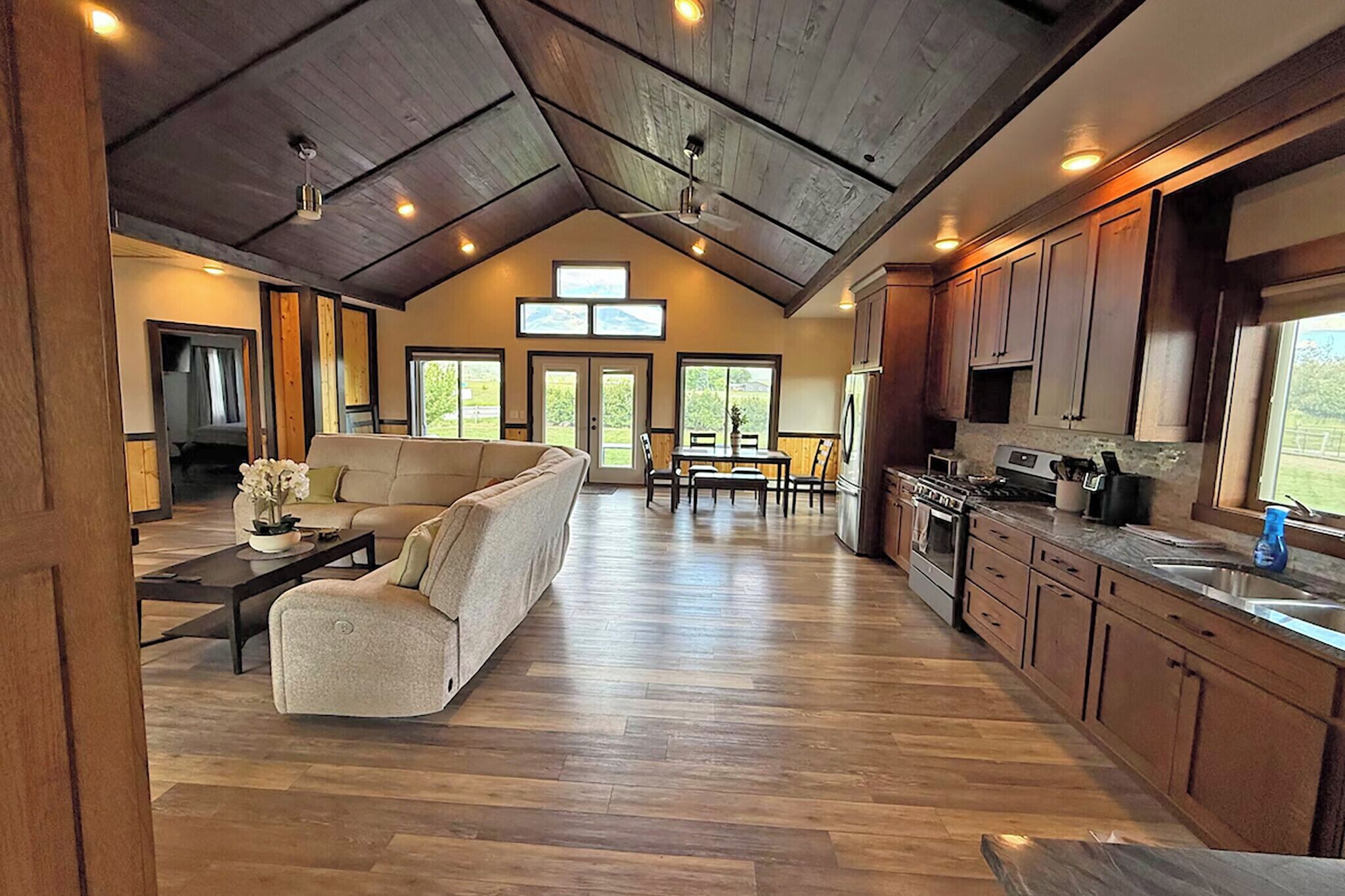 A spacious living area with a sofa, dining table, and kitchen with wooden cabinets and appliances.