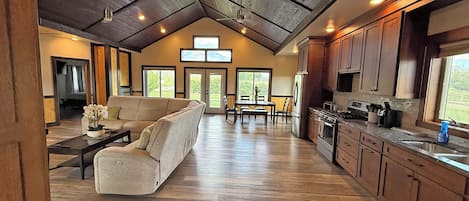 A spacious living area with a sofa, dining table, and kitchen with wooden cabinets and appliances.
