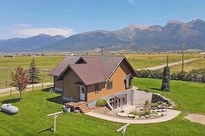 Ein zweistöckiges Haus mit geneigtem Dach, einer Veranda und einem gepflegten Rasen.