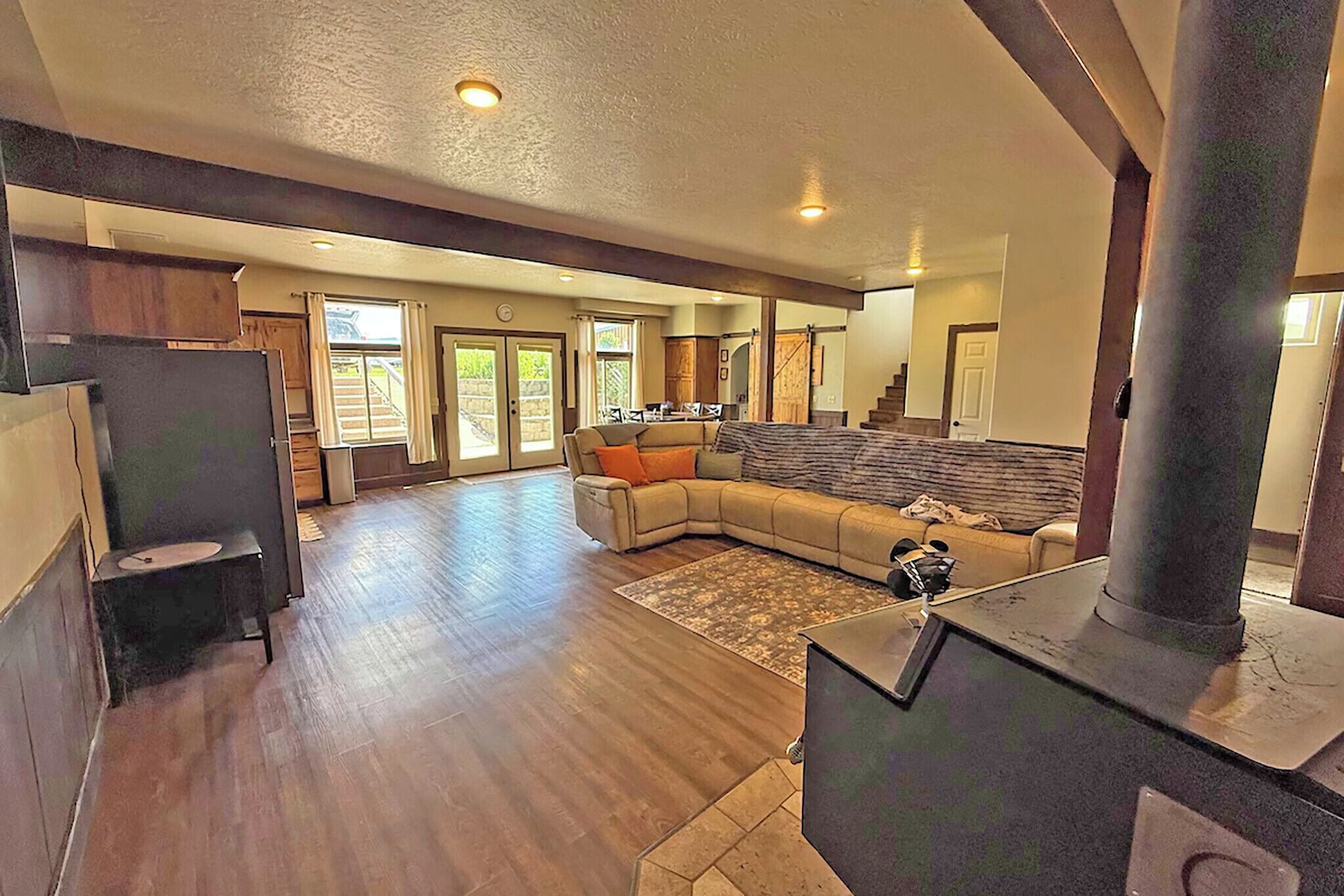 A spacious living area with a large sectional sofa, a fireplace, and a view of the outside through a sliding glass door.