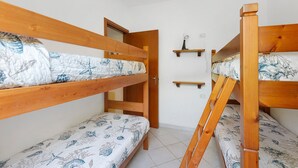 A room with bunk beds, a door, and a small shelf with a light fixture. - Three-Room Apartment with Garden 100 Meters from the Beach - Sole e Mare Tourist Village (Rio)