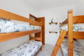 Ein Zimmer mit Etagenbetten, einer Tür und einem kleinen Regal mit einer Lampe.