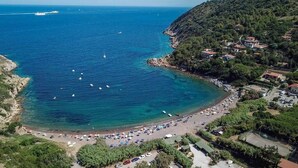 Una zona costera con playa, barcos y un pueblo.