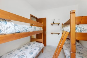 A room with bunk beds, a door, and a small shelf with a light fixture. - Three-Room Apartment with Garden 100 Meters from the Beach - Sole e Mare Tourist Village (Rio)