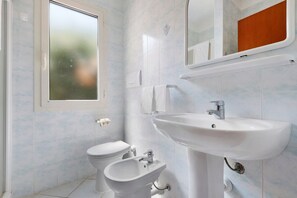 A bathroom with a toilet, bidet, and sink. - Three-Room Apartment with Garden 100 Meters from the Beach - Sole e Mare Tourist Village (Rio)