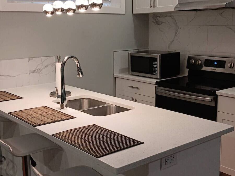 A modern kitchen with a central island, stainless steel appliances, and a window with blinds.