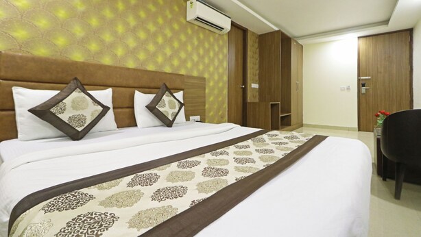 A hotel room with a large bed, a wooden headboard, an air conditioning unit, a wardrobe, and a desk with a chair. - HOTEL RONIT ROYAL - DELHI AIRPORT  (New Delhi)