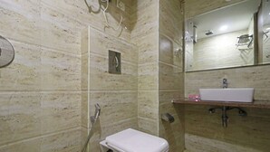 A bathroom with a toilet, a sink, a mirror, and a shower. - HOTEL RONIT ROYAL - DELHI AIRPORT  (New Delhi)